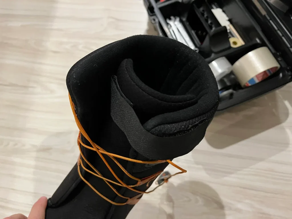 ThirtyTwo Shifty snowboard boot with a DIY velcro fix to keep the tongue from sliding, shown indoors with orange laces.