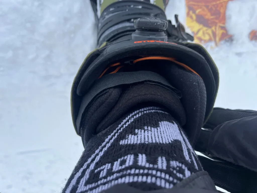 Close-up of a ThirtyTwo Shifty snowboard boot after riding, showing the DIY velcro strap holding the tongue centered and preventing it from sliding.