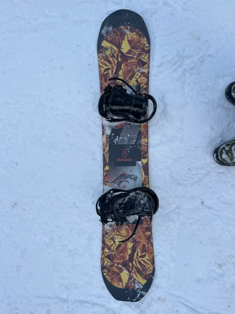 Bataleon FunKink snowboard (154 cm, 2024 model) lying on the snow with bindings mounted, photographed from above.