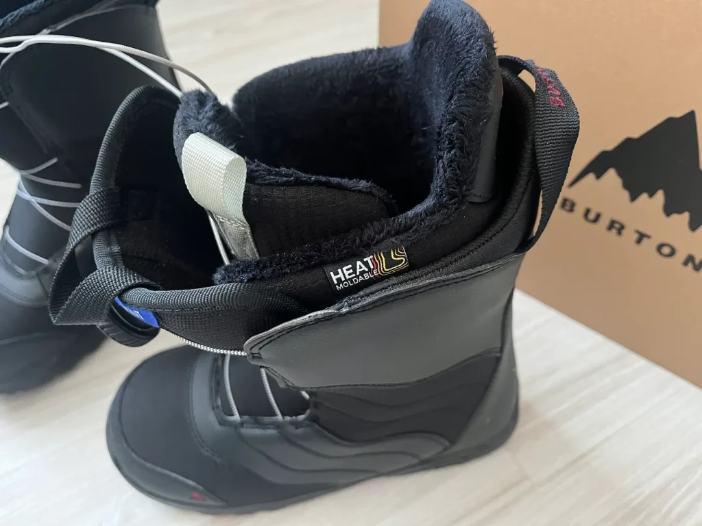 Close up of a Burton Mint BOA snowboard boot showing the “HEAT MOLDABLE” label on the liner, with the boot open and a Burton box in the background.
